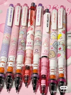 several pens are lined up on a pink background with hello kitty characters and other items