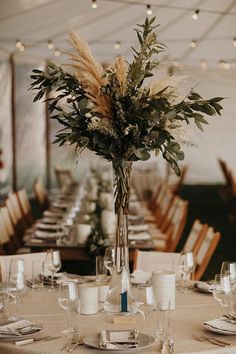 a vase with flowers on top of a table set for a formal dinner or party