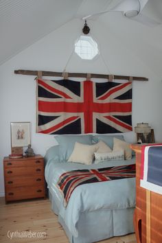 a bedroom with a flag hanging over the bed and dressers in front of it