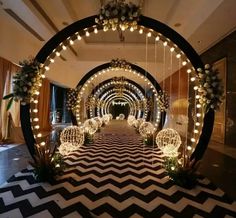 an archway decorated with lights and balls in the middle of a room filled with black and white chevron flooring