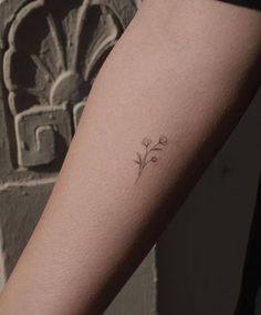 a woman's arm with a small flower tattoo on the left side of her arm