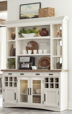 a white china cabinet with glass doors and shelves filled with dishes on top of it