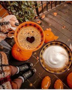 two people sitting on the ground with pumpkins and drinks