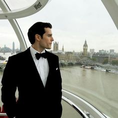 a man in a tuxedo looks out over the water from a boat deck