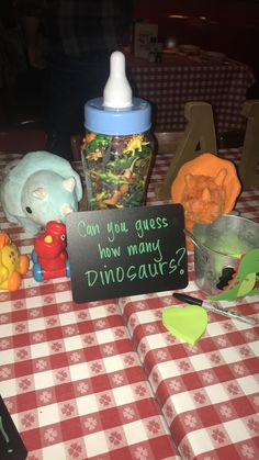 a baby bottle sitting on top of a red and white checkered table cloth next to other toys