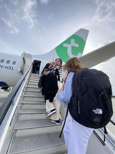 people boarding an airplane with their luggage on the stairs