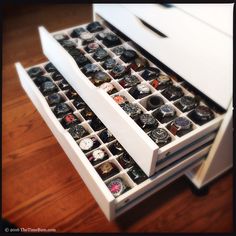 two drawers with watch parts in them on a wooden floor next to a white dresser