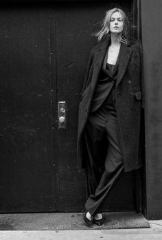 black and white photograph of woman leaning against door