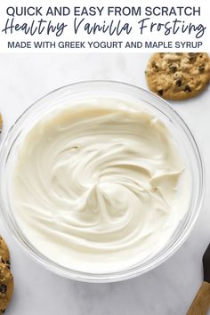 a bowl filled with white frosting next to cookies and chocolate chip cookies on the side