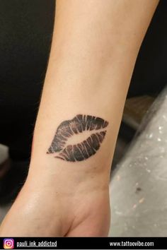 a woman's hand with a tattoo on it that has a black lipstick imprint