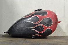 a black and red motorcycle helmet sitting on top of a wooden table next to a white wall