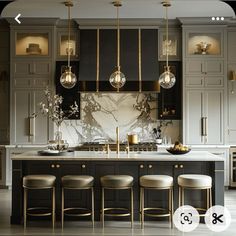 a kitchen with marble counter tops and gold accents on the cabinets, along with bar stools