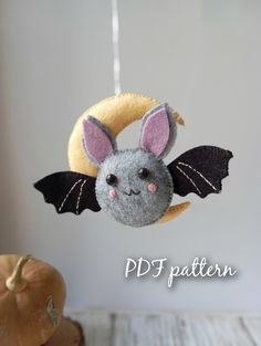 a felt bat hanging from a string on top of a wooden table next to a pumpkin