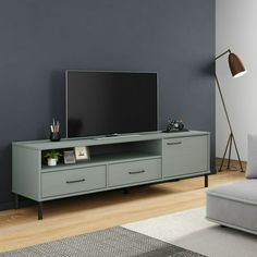 a living room with a gray couch and television on top of the entertainment center in front of a blue wall