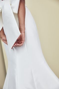 the back of a woman's white dress with a large bow at the waist