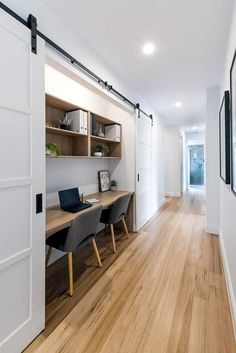 an open door leading to a room with wooden floors and white walls, along with two desks