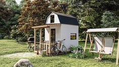 a tiny house with a porch and swing set in the grass next to a rock