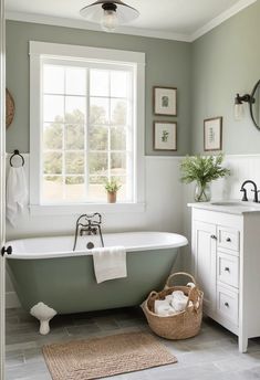 A spacious farmhouse bathroom with a small cabinet in Sherwin Williams Evergreen Fog, a large white-framed window, light-colored walls, and rustic wooden accents. Evergreen Fog, Colored Walls, Farmhouse Bathroom Design, Bathroom Vanity Designs, Vanity Design, Small Cabinet, Minimal Decor, Farmhouse Bathroom, Painting Cabinets