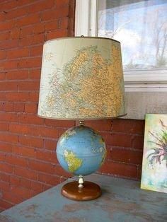 a lamp sitting on top of a wooden table next to a brick wall and window