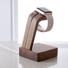 an apple watch and wooden stand on a white countertop with a window in the background