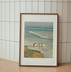 two surfers on the beach with their surfboards in front of white tiled walls