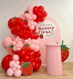 a bunch of balloons and strawberries are on the floor next to a pink trash can