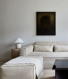 a living room with white furniture and a large painting on the wall above the couch