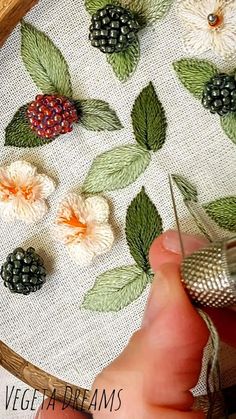 someone is working on an embroidery project with flowers and leaves