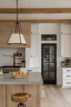 a kitchen with white cabinets and an island that has fruit on it in the center