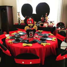 a mickey mouse themed birthday party with red and black table cloths, plates and decorations