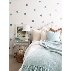 a bedroom with blue polka dot decals on the wall and a white bed in front of it