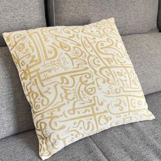 a gray couch with a yellow and white pillow sitting on it's back end