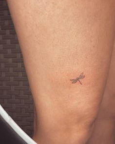 a small dragonfly tattoo on the back of a woman's leg and thigh