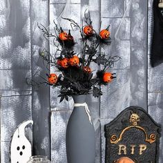 a vase filled with orange flowers sitting on top of a table next to a tombstone