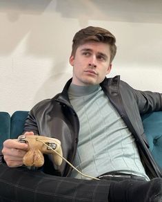 a man sitting on top of a blue couch holding a remote control in his hand