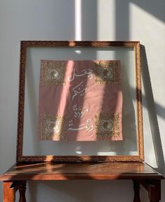 a wooden table topped with a framed piece of art