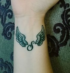 a small wrist tattoo with wings on it