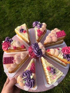 a person holding a plate with cakes on it in the shape of hearts and flowers