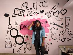 a woman standing in front of a wall with black and pink doodles on it