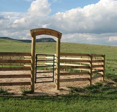 a wooden gate in the middle of a grassy field