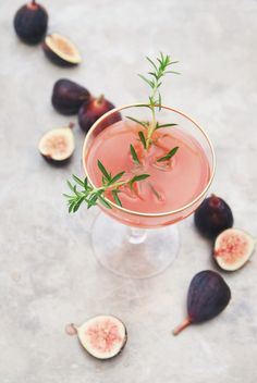 a glass filled with a drink surrounded by figs