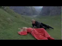 a man laying on top of a lush green hillside next to a blonde haired woman