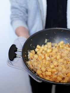 a person holding a frying pan filled with food