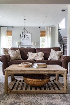 a living room with couches, coffee table and chandelier in the background