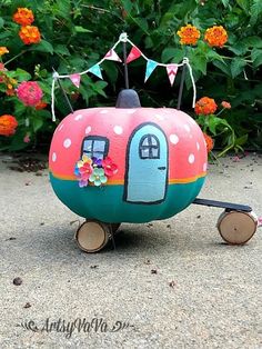 a painted rock shaped like a trailer with flowers and bunting on the front door