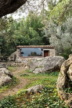 an outdoor area with large rocks and trees in the foreground, surrounded by greenery