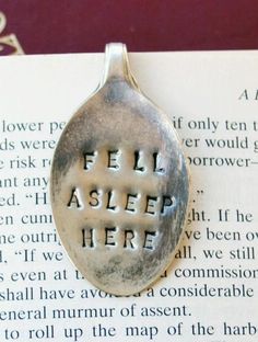 a spoon with the words fell asleep here on it sitting next to an open book