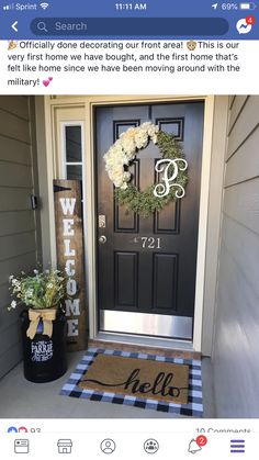 a black door with a welcome mat and white flowers