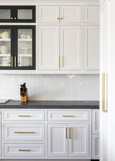 a kitchen with white cabinets and black counter tops, gold trim on the door handles