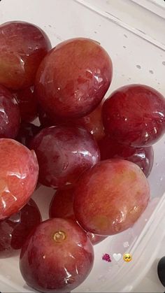 a plastic container filled with plums on top of a table